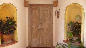 A wooden door with two potted plants on either side, a wall-mounted light, and a small decorative item above the door. - Best Location in Sayulita.Stunning Ocean Views. 2 min walk to beach (Sayulita)