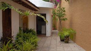 A narrow courtyard with a tiled floor, surrounded by plants and a white building with a brown roof. - Best Location in Sayulita.Stunning Ocean Views. 2 min walk to beach (Sayulita)