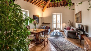 Un salon spacieux avec une table à manger en bois, des sièges confortables, une grande fenêtre et une cheminée accueillante.