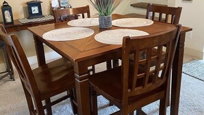 Une table à manger avec quatre chaises, un vase avec une plante et un tableau encadré au mur.