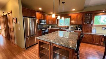 A kitchen with wooden cabinets, stainless steel appliances, granite countertops, and pendant lighting.