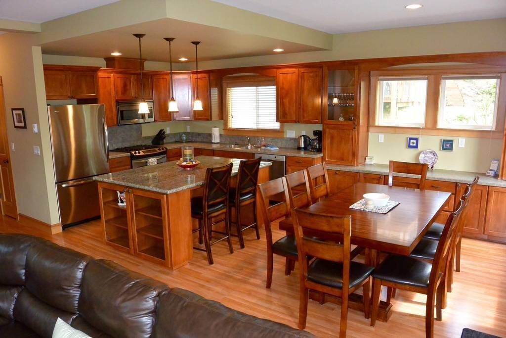 A modern kitchen with wooden cabinets, stainless steel appliances, and a central island with seating.