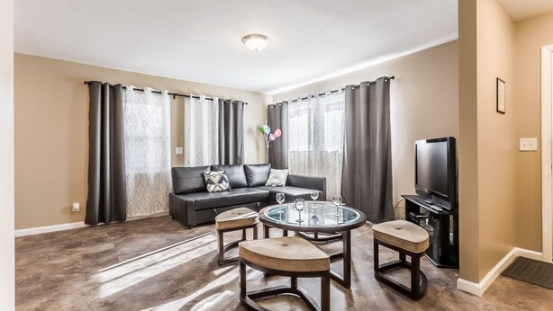 A living room with a sofa, a glass-top coffee table, and a television.