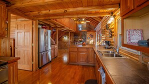 A spacious kitchen with wooden cabinets, a stainless steel refrigerator, and a large island with a sink.