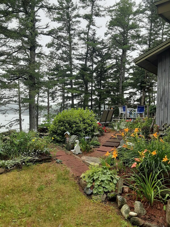 A garden with a wooden deck, chairs, and a pond.