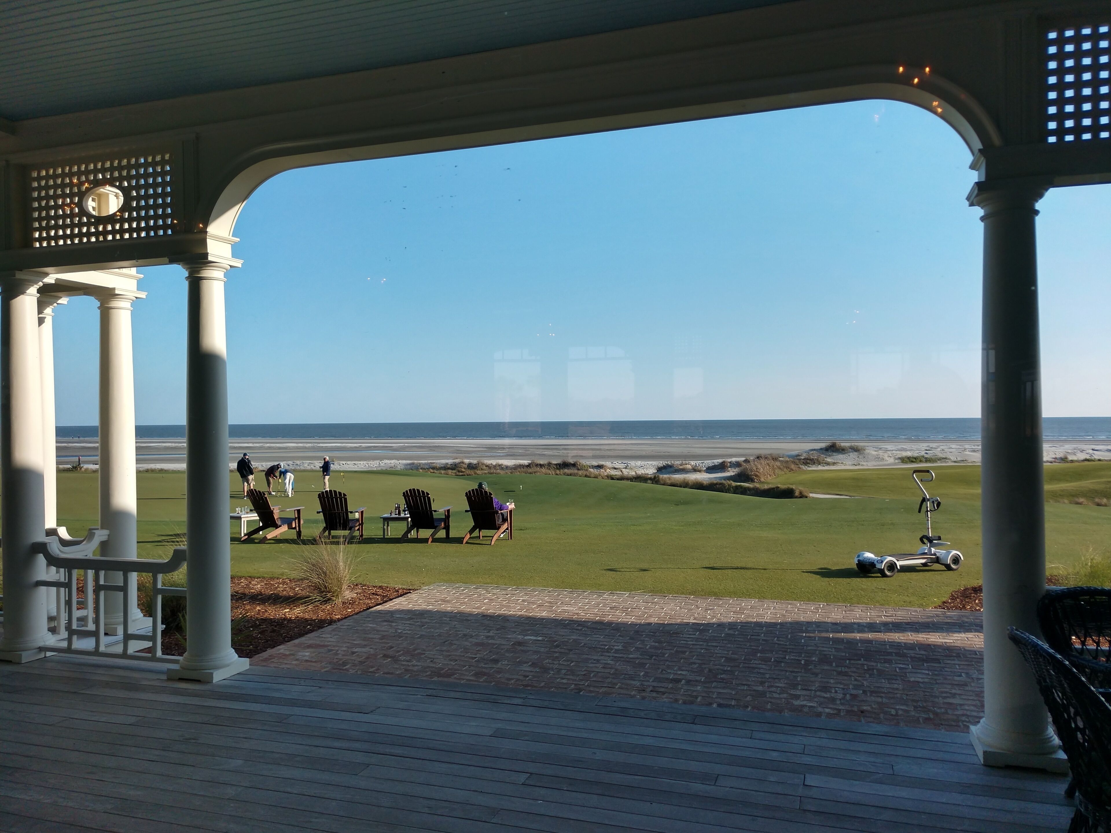 A covered area with a view of a golf course and the ocean.