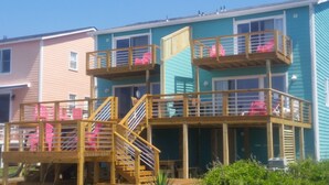 A multi-level wooden deck with railings and stairs, attached to a building with multiple balconies.