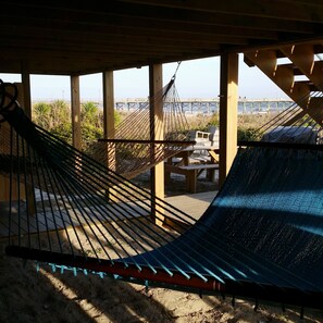 Una hamaca bajo una estructura de madera con vista a un muelle y una playa.