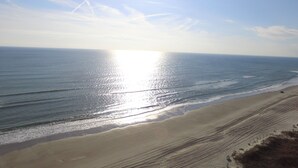 A beach with a clear sky and the sun reflecting on the water.