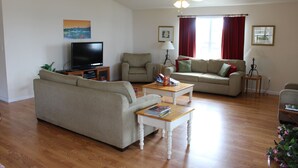 A living room with a sofa, a television, a coffee table, and a ceiling fan.