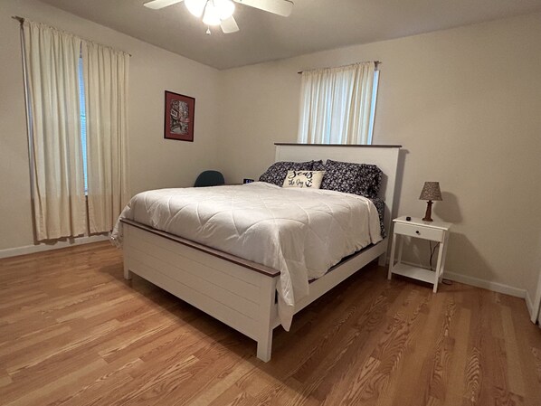 A bedroom with a bed, a nightstand, a lamp, and a ceiling fan. - Water Front Beach House on the Bay, Boat Launch, Great Sunsets & Tiger Beach (Pass Christian)