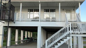 A two-story building with a balcony, outdoor seating, and a staircase.