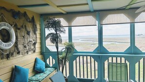Habitación con vista a un paisaje costero, un flotador en la pared y un banco con cojines.