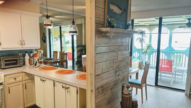 Una cocina con armarios blancos, una isla de madera y un comedor con sillas y una mesa.