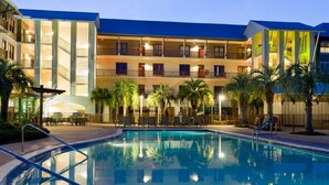 Ein Hotel mit Swimmingpool, mehreren Balkonen und Palmen.