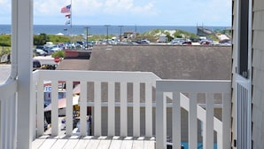 A balcony with a view of a parking lot and ocean.
