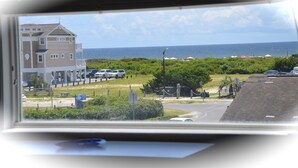 A view of a coastal area with a large building, parked cars, and a clear sky.