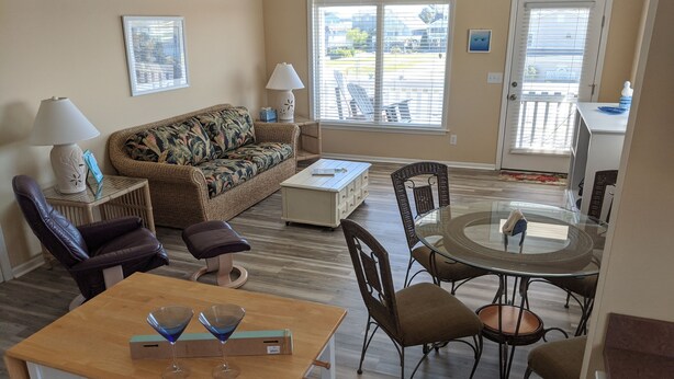 A living room with a sofa, chairs, a coffee table, and a dining table.