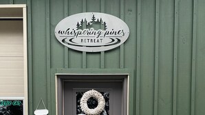 Eine Tür mit einem Kranz, einem Willkommensschild und einem Schild für Whispering Pines Retreat.