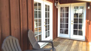 A wooden porch with two doors, a bench, and a small table. - The Redwood Hearts Cottage in Cambria (Cambria)