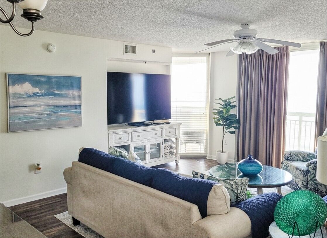 Ein Wohnzimmer mit einer Couch, einem Fernseher und einem Deckenventilator.