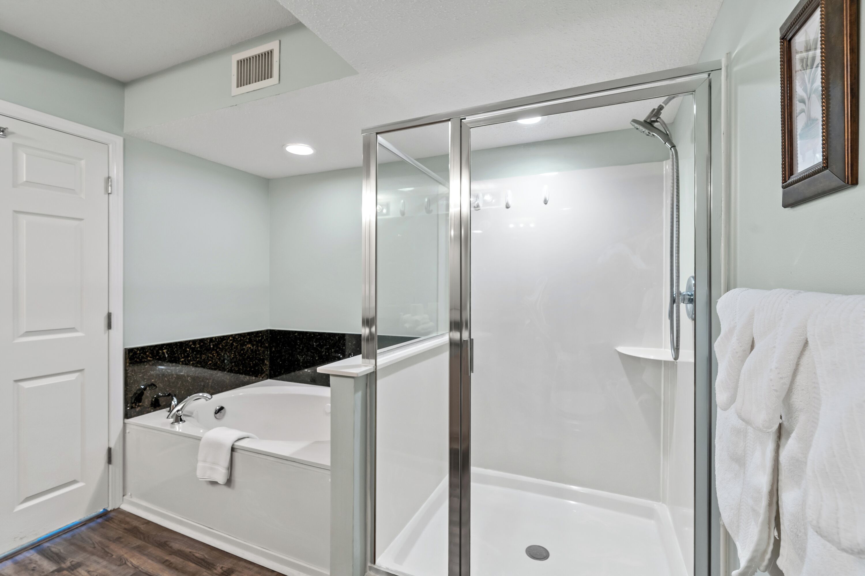 Une salle de bain moderne dotée d’une douche à parois de verre, d’une baignoire sur pieds et d’un meuble-lavabo avec un plan de travail noir.