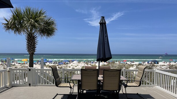 Une terrasse en bois avec des sièges extérieurs et une vue sur la plage.
