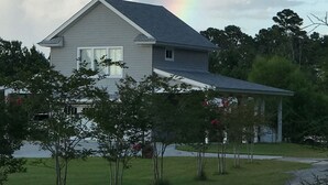 Ein Haus mit einem geneigten Dach und einem gut sichtbaren Regenbogen am Himmel.