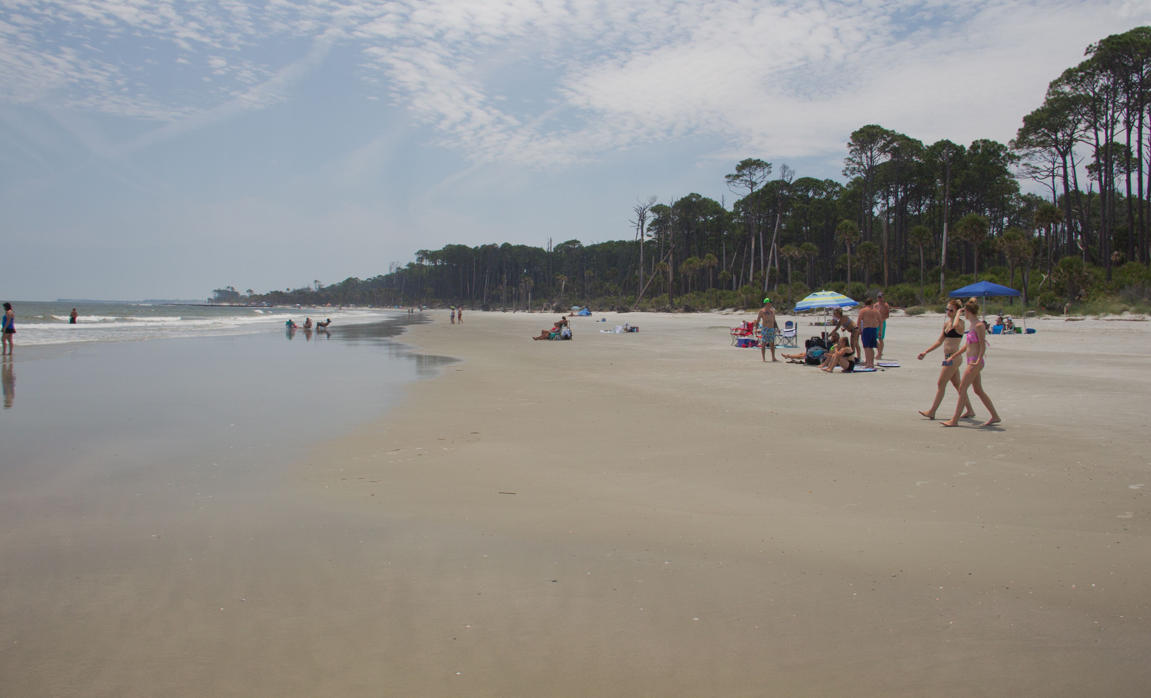 A beach with people, umbrellas, and beach chairs.