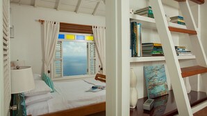 A bedroom with a bed, a window with curtains, a bookshelf, and a ladder.