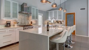 Una cucina moderna con isola centrale, elettrodomestici in acciaio inossidabile e sgabelli da bar.