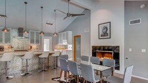 Una cucina moderna con rivestimento in mattoni, una zona pranzo con tavolo in vetro e sedie grigie, e un camino.