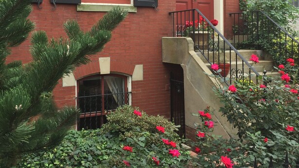Un bâtiment en briques rouges, avec des volets noirs, une porte rouge et le numéro « 415 » au-dessus de l’entrée.
