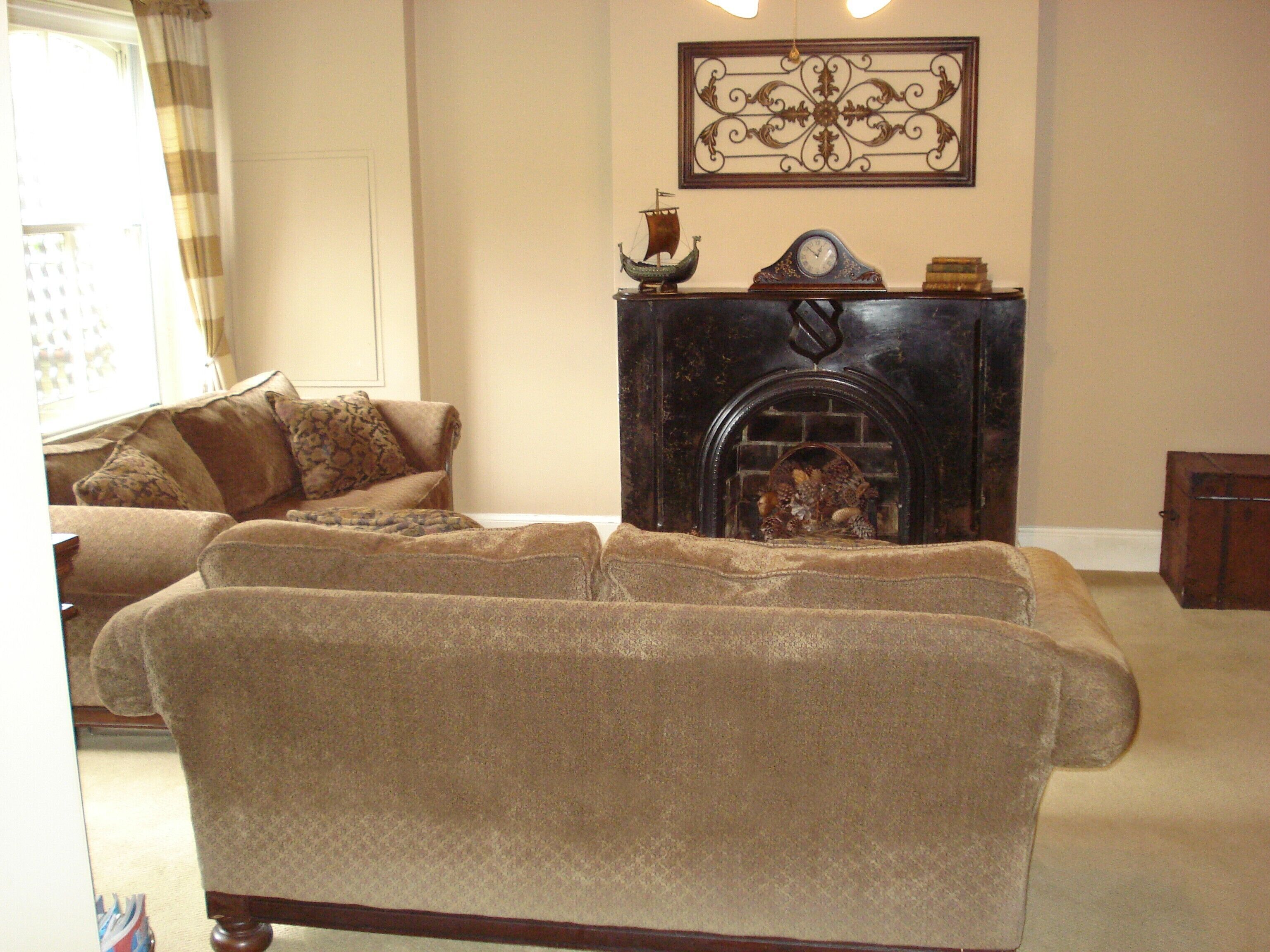 A living room with a fireplace, two sofas, and a decorative wall piece.