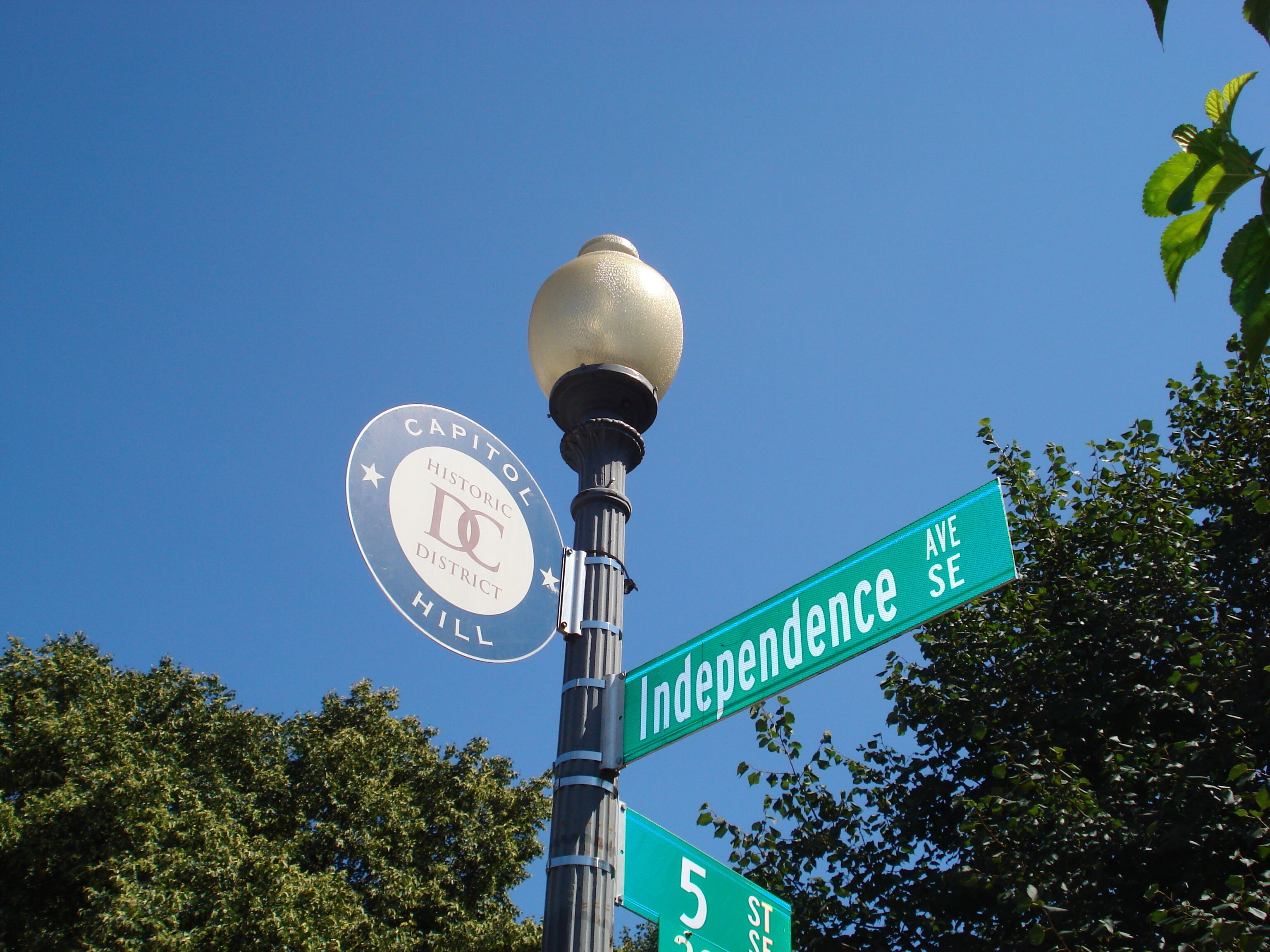 Un panneau de signalisation indiquant « Independence St » et « 5th St », un emblème du quartier historique et un lampadaire.