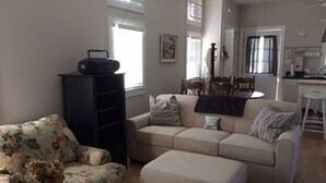 Una sala de estar con un sofá, un sillón floral y un mueble negro para entretenimiento.