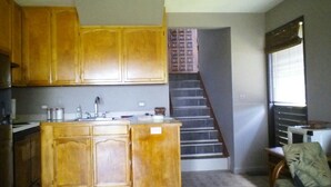 Eine Küche mit Holzausstattung, einer Spüle und einer Treppe, die zu einer weiteren Ebene führt.
