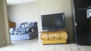 Ein Schlafzimmer mit einem Bett, einem Fernseher auf einem Holzschrank und einem Kühlschrank.