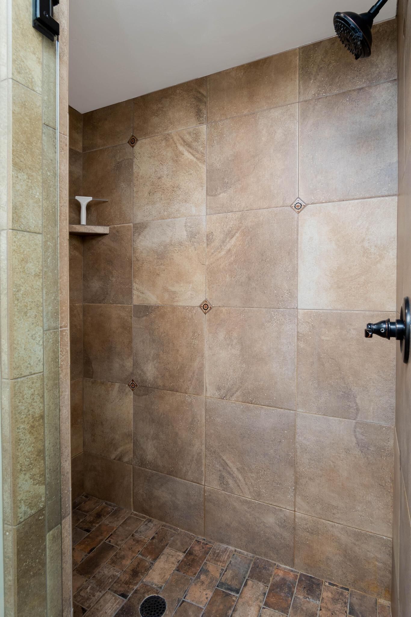Un espace douche avec des carreaux de couleur beige et un plancher en bois.