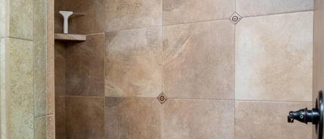 Un espace douche avec des carreaux de couleur beige et un plancher en bois.