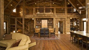 A spacious wooden interior with a high ceiling, a dining area with a table and chairs, and a cozy seating area with a sofa. - Book for fall and winter now… dates are filling up!! (Maple)