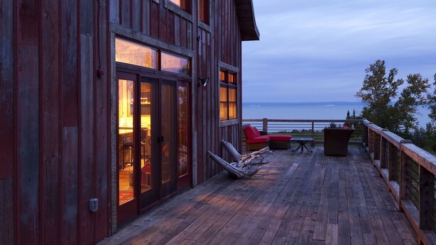 A wooden deck with a view of the sea, a red chair, and a table. - Book for fall and winter now… dates are filling up!! (Maple)