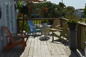 A wooden deck with outdoor seating, including chairs and a table. - Home With Cottage Feel Offering Golf Cart, Kayaks, Bikes, Fishing (Goodland)