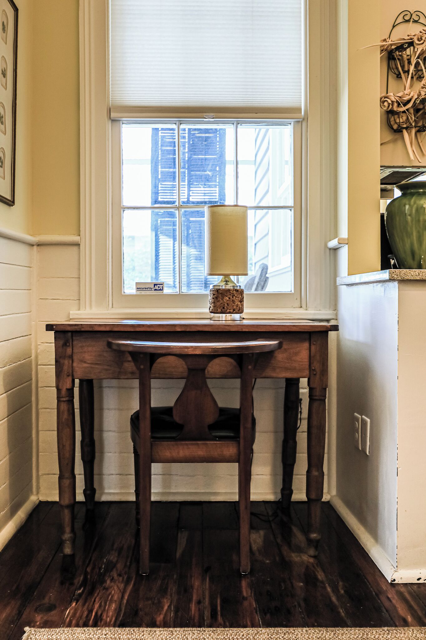 A wooden table with a lamp in front of a window with blinds.