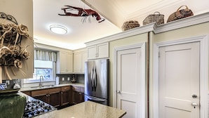 A kitchen with granite countertops, a stainless steel refrigerator, and wooden cabinets. - Jingle Bells Square House (Savannah)