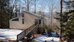 Une cabane dotée d’une terrasse en bois et d’un escalier menant à une zone abritée.