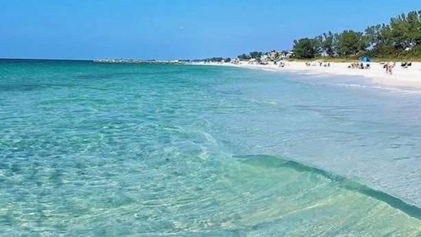 A beach with clear turquoise water and white sand.