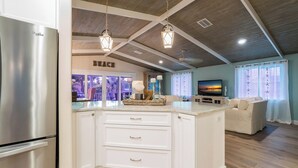 A spacious kitchen with a central island, white cabinetry, and a stainless steel refrigerator.