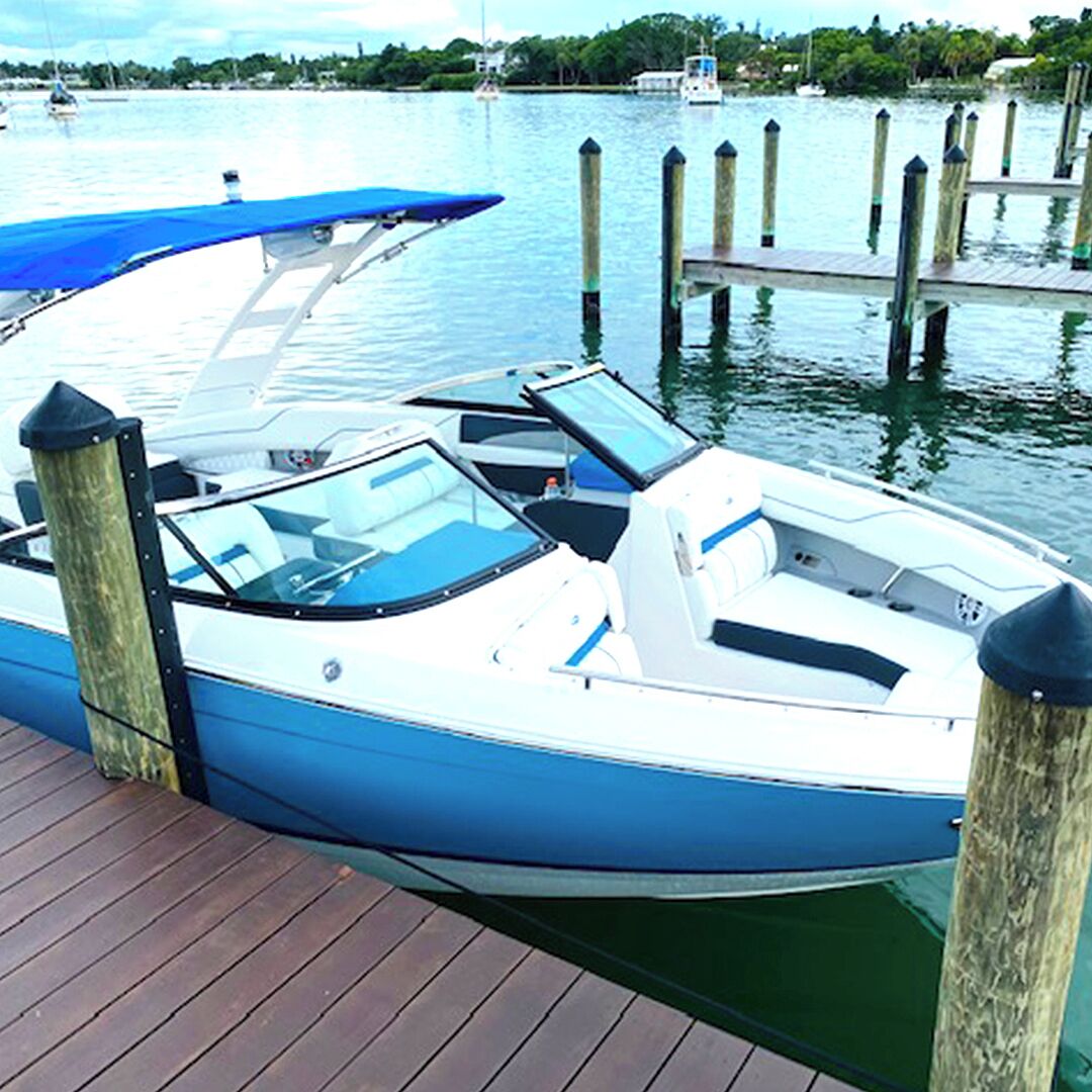 A small motorboat docked at a wooden pier with a clear view of the water and distant shoreline.