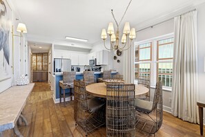 A spacious kitchen with white cabinets, a central island, and a dining area with wicker chairs and a round table. - Stunning Views, Remodeled Dec 2025! Reduced rates for remaining days of June!! (Gulf Shores)